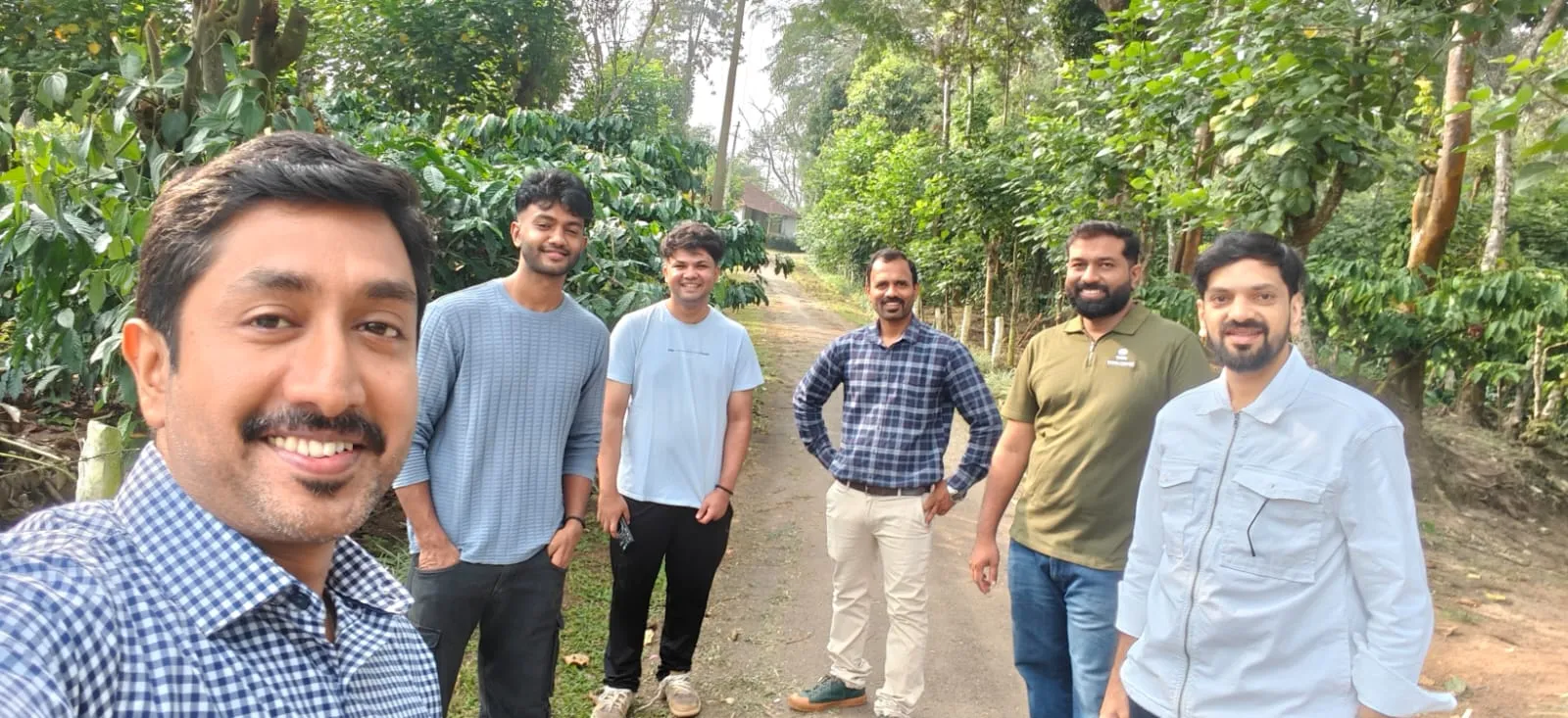 A selfie of our team and the estate staff on a path through the coffee plantation.